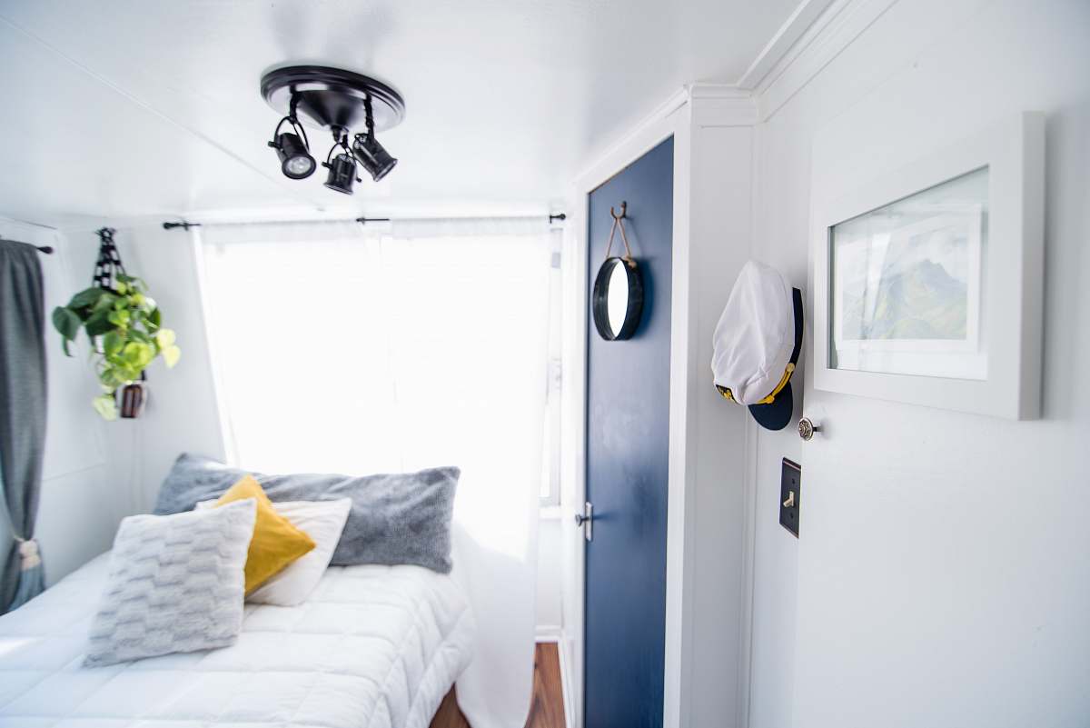 interior design four pillows on quilted white bed near blue door and window with white curtain inside well-lighted room bed